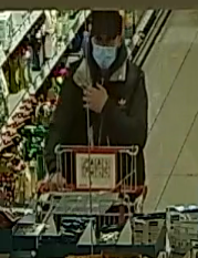 Frontfoto von Täter 3 (mit Mund-Nasenschutz) im Geschäft und mit einem Warenkorb.